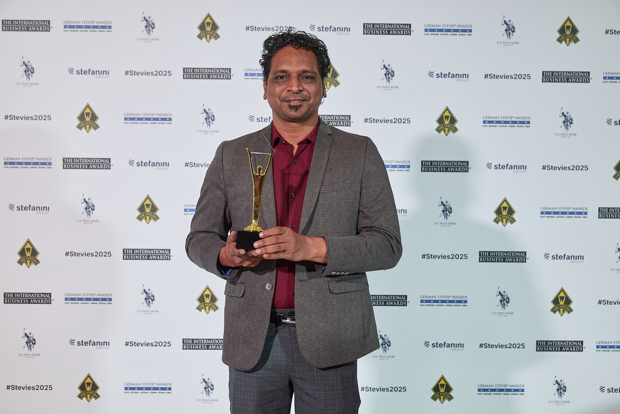 Chirag Patel holding Stevie Award trophy at ceremony in Lisbon, Portugal 2025, representing Hidden Brains